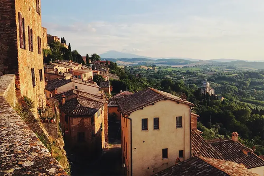 Bergsby med tegeltak och utsikt över böljande kullar i Toscana
